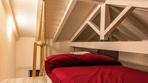 A dormitory-style room with a bunk bed, wooden beams, and a sloped ceiling. - Alborghetto2 (Gerace)