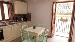 A kitchen with a dining table and chairs, a sink, cabinets, and a view of the outside balcony. - Alborghetto2 (Gerace)