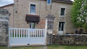 A stone building with a white gate, a small window, and a number plaque. - GÎTE SARAZAC (Mayac)