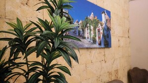 Una habitación con pared de ladrillo color beige, sofá de cuero marrón y una planta en maceta.