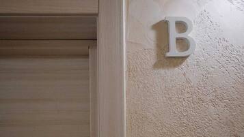 A wooden door with a textured wall and a letter 'B' mounted on it.