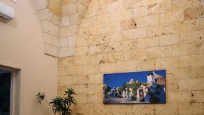 Un comedor con pared de piedra, una pintura y una mesa con sillas.