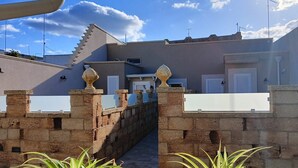 Un portón de piedra que da a un edificio de diseño moderno, con techo plano y un pequeño jardín.