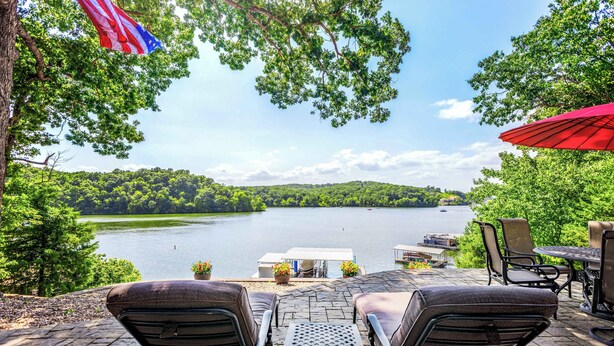 An outdoor patio with a view of a lake, surrounded by trees and a dock. - Lakeside Oasis Room for 12! (Linn Creek)