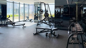 Un gimnasio moderno con diversos equipos de ejercicio, amplias ventanas y un diseño limpio y espacioso.