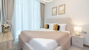 Habitación de hotel con una cama grande, una mesita de noche con lámpara y dos cuadros en la pared.