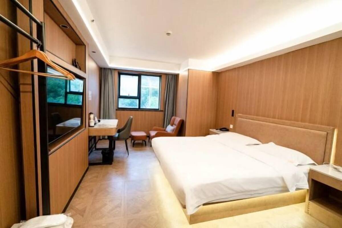 Een hotelkamer met een bed, bureau, stoel, kast en raam.