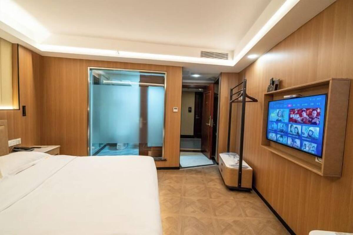 Een hotelkamer met een bed, een televisie, een kledingkast en een spiegel.