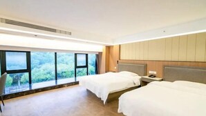 Une chambre d’hôtel avec deux lits, une grande fenêtre et une vue sur les arbres.