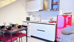 Une cuisine compacte équipée d’un four à micro-ondes, d’un évier et d’un réfrigérateur rouge.