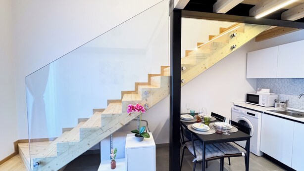 Une cuisine moderne avec un coin repas, un escalier et un lave-linge.