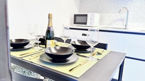 Eine moderne Küche mit Esstisch für zwei Personen, ausgestattet mit schwarzen Schüsseln, Weingläsern und einer Champagnerflasche.