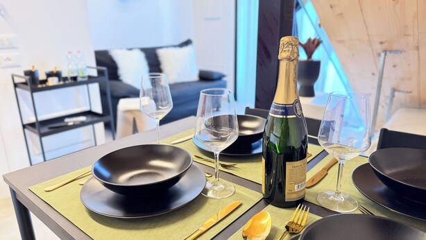 Ein Tisch mit schwarzen Tellern, Weingläsern und einer Flasche Francois Montand Champagner.