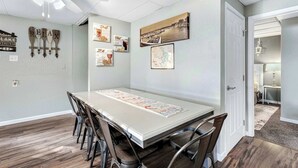 Uma área de refeições com uma mesa comprida, cadeiras e um ventilador de teto.