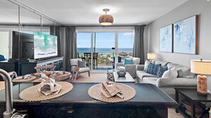 A modern hotel room with a large balcony, a dining area, and a living space. - Sterling Shores 616 (Destin)