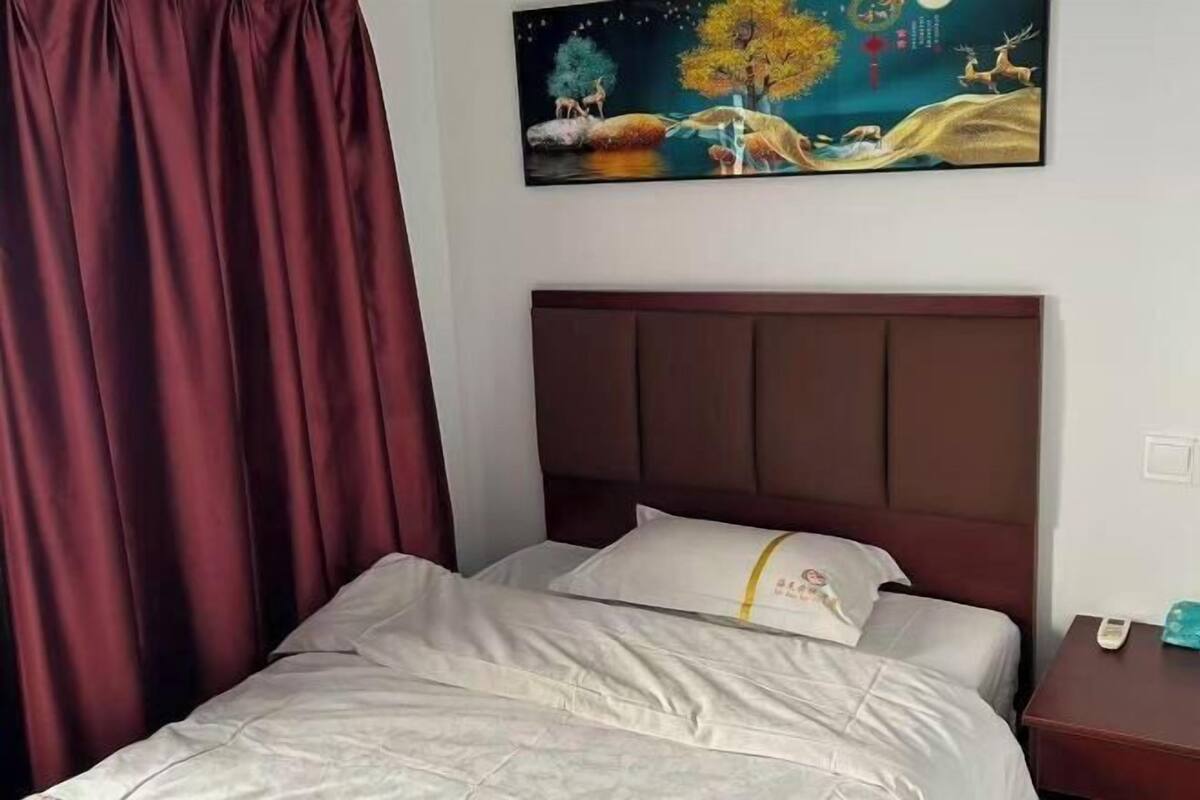 A hotel room with a bed, a nightstand, and a painting on the wall.
