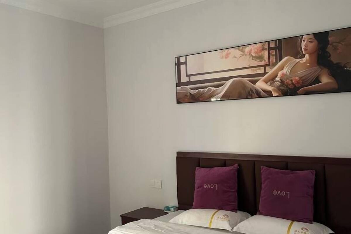 A hotel room with a bed, two nightstands, and a large framed artwork above the bed.