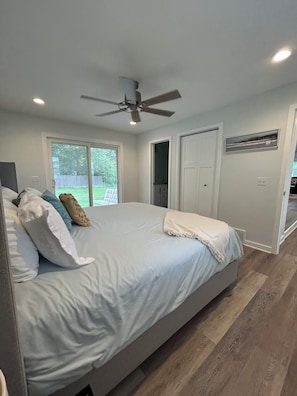 Une chambre à coucher avec un lit, un ventilateur de plafond, une fenêtre et une porte.