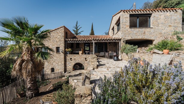 A stone house with a patio, a stone fireplace, and a wooden fence.