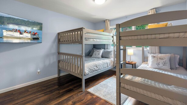 A room with a bunk bed, a flat-screen TV mounted on the wall, and a wooden floor. - Ozark Escape - Enjoy Resort-style Fun (Osage Beach)