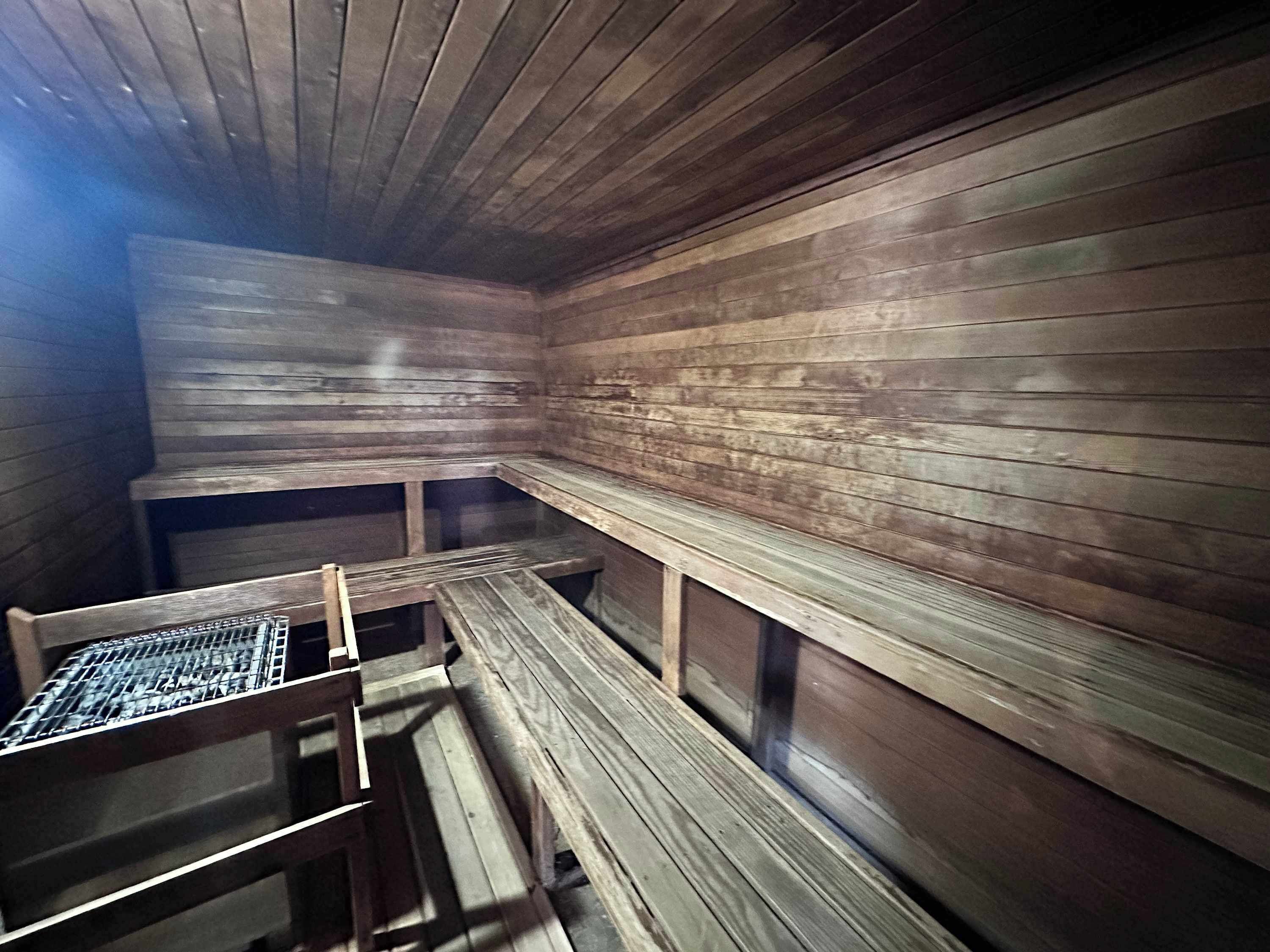 A sauna with wooden benches and a metal grid on one side.