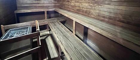 A sauna with wooden benches and a metal grid on one side.