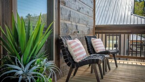 A wooden deck with two black chairs and a potted plant. - *Modern 3BD Cabin w/ Hot Tub + Arcade! Near TOWN!* (Pigeon Forge)