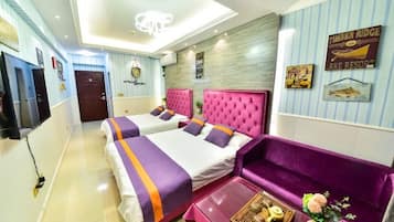 A hotel room with two beds, a sofa, a TV, and a ceiling light.