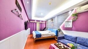 A compact room with a bed, a sofa, and a small table with snacks. - Huangsheng Hotel (Quanzhou Food Street) (Quanzhou)