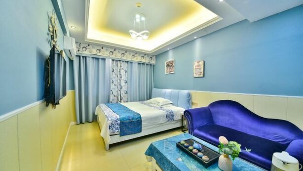 A room with a bed, a sofa, a coffee table with a tray of snacks, and a ceiling light fixture. - Huangsheng Hotel (Quanzhou Food Street) (Quanzhou)