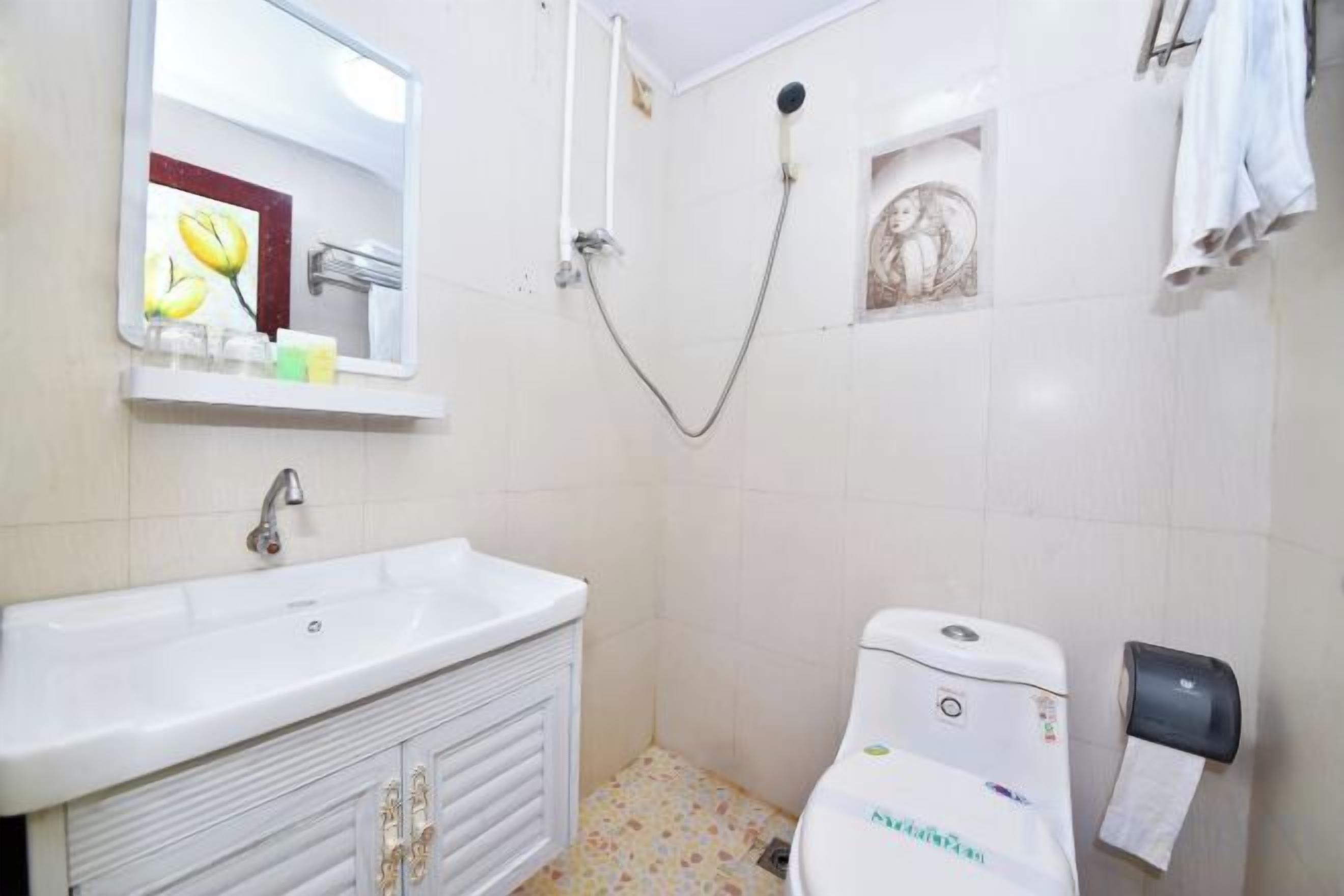A bathroom with a sink, toilet, shower, and towel rack.