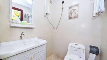 A bathroom with a sink, toilet, shower, and towel rack.
