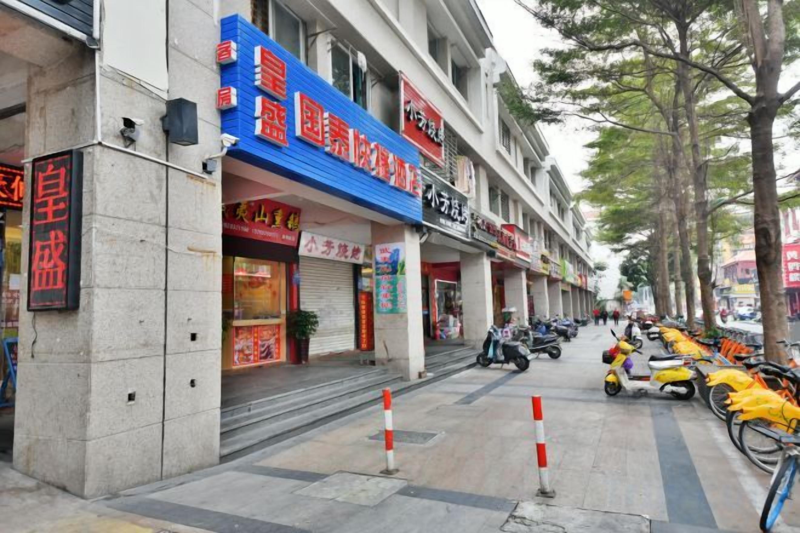Calle con tiendas, una tienda cerrada con un letrero rojo y scooters estacionados.