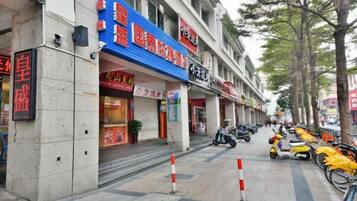 Calle con tiendas, una tienda cerrada con un letrero rojo y scooters estacionados.