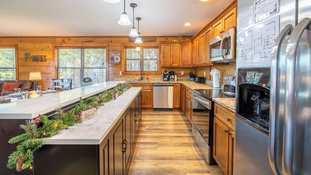 A modern kitchen with wooden cabinets, stainless steel appliances, and a central island with a Christmas garland.