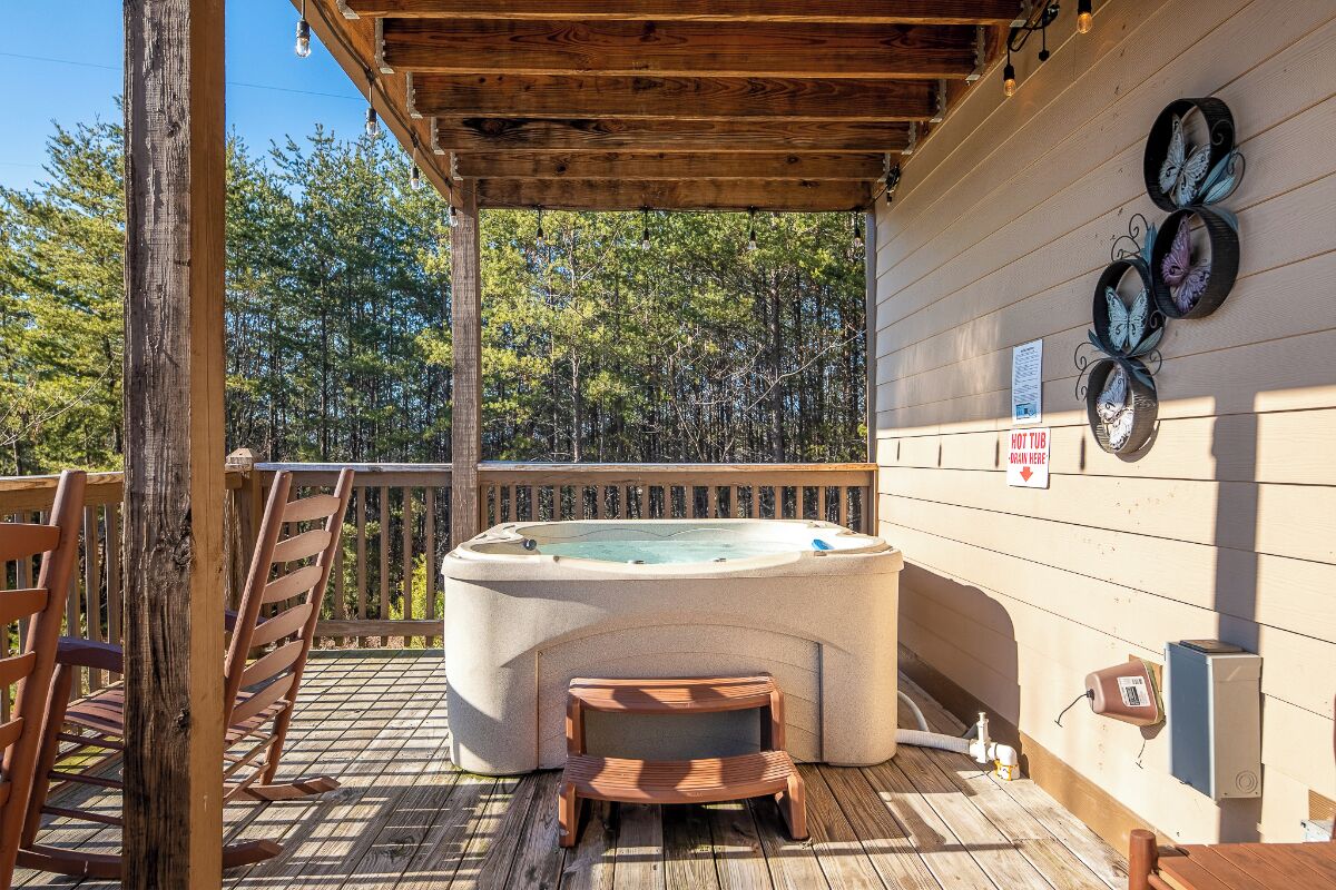 A hot tub on a wooden deck with a wooden chair and a small wooden stool.