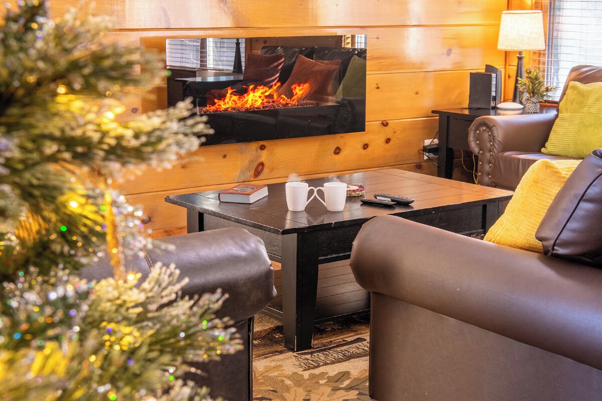 A cozy living room with a fireplace, leather sofa, and a coffee table.