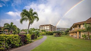 A hotel with a central courtyard, palm trees, and a rainbow in the sky.