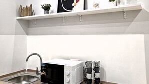 A modern kitchen with white cabinetry, a microwave, a sink, and a countertop with a toaster and decorative items.