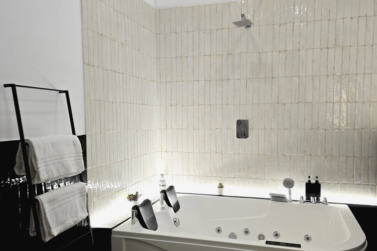 Ein modernes Badezimmer mit freistehender Badewanne, einem Handtuchhalter und einem kleinen Topfpflanzen.