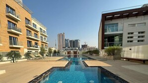 Un immeuble d’appartements moderne doté d’une piscine sur le toit, de grandes fenêtres et offrant une vue dégagée sur le paysage urbain.