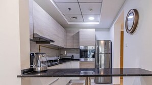 Une cuisine moderne dotée d’appareils électroménagers en acier inoxydable, d’un plan de travail noir et d’un éclairage encastré au plafond.