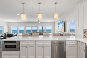 A modern kitchen with a large island, stainless steel appliances, and pendant lighting.