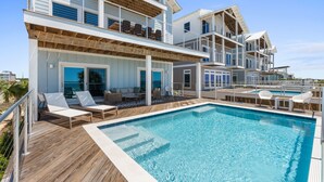 A multi-story building with a swimming pool, outdoor seating, and balconies. - Clementine: 7 Bedrooms, Beachfront in Mexico Beach, Private Pool, Game Room (Mexico Beach)