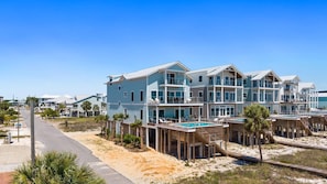 A beachfront hotel with multiple balconies, a swimming pool, and a sandy beach area.