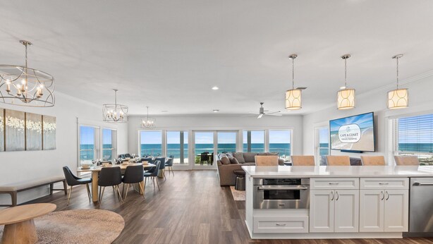 A spacious open-plan living area with a kitchen, dining space, and large windows offering ocean views. - Clementine: 7 Bedrooms, Beachfront in Mexico Beach, Private Pool, Game Room (Mexico Beach)