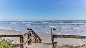 Een houten vogelzangpad leidt naar een strand, met een helder uitzicht op de oceaan.