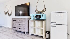 Een moderne keuken met een witte koelkast, een magnetron en een koffiezetapparaat op een houten aanrecht.