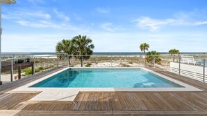 A wooden deck with a swimming pool, palm trees, and a beach view. - Daiquiri: Beachfront in Mexico Beach, Private Pool, Pet Friendly (Mexico Beach)