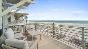 Een balkon met uitzicht op het strand, een houten terras en buitenmeubilair.